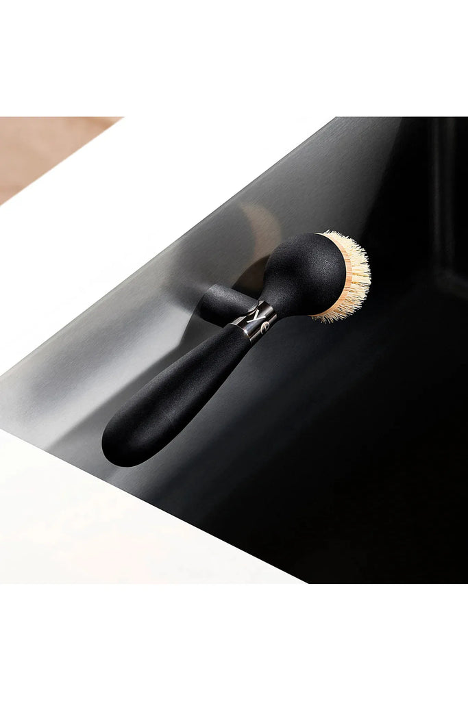 Yeseco.life One Brush The Ultimate Dish Brush Black Handle. Looking down on the Dish Brush being held by the magnetic holder inside a sink.