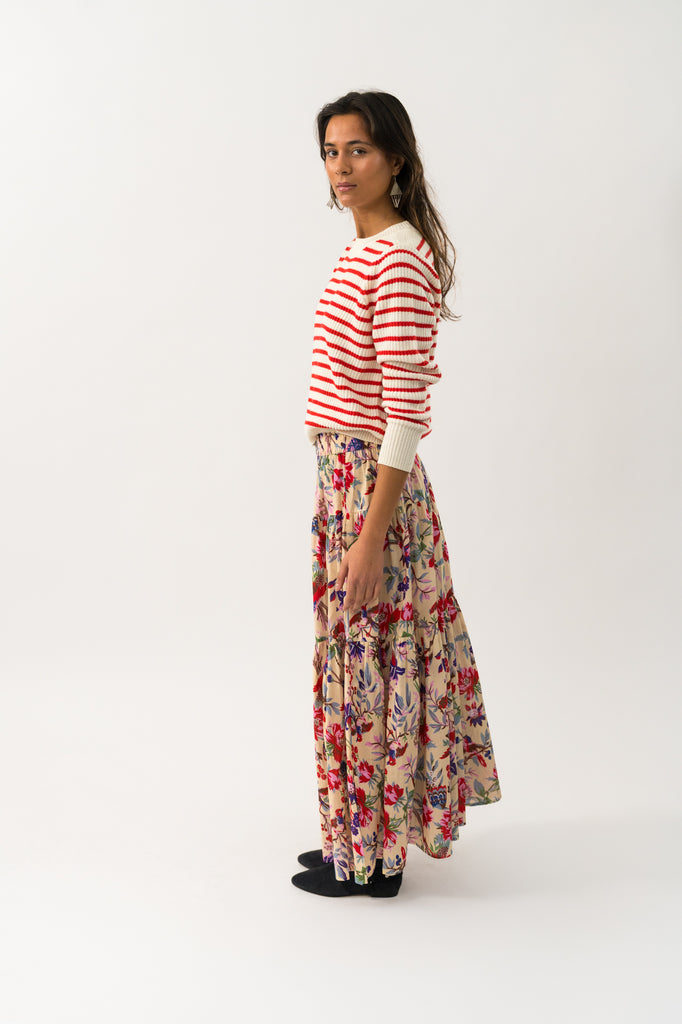 Woman wearing a striped sweater and floral skirt on a white background. Lollys Laundry Sunset Maxi Skirt in floral print.