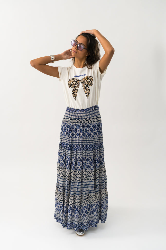 Woman wearing a white t-shirt with a leopard print bow design and patterned skirt. Lollys Laundry Roma Tee White.