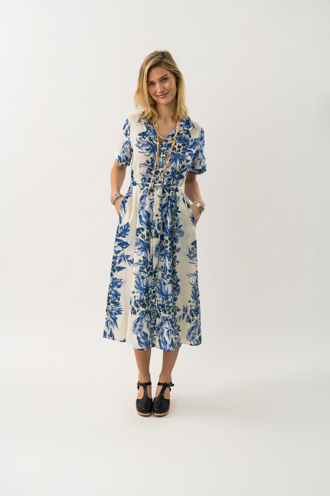 Woman wearing a blue and white floral dress on a white background.