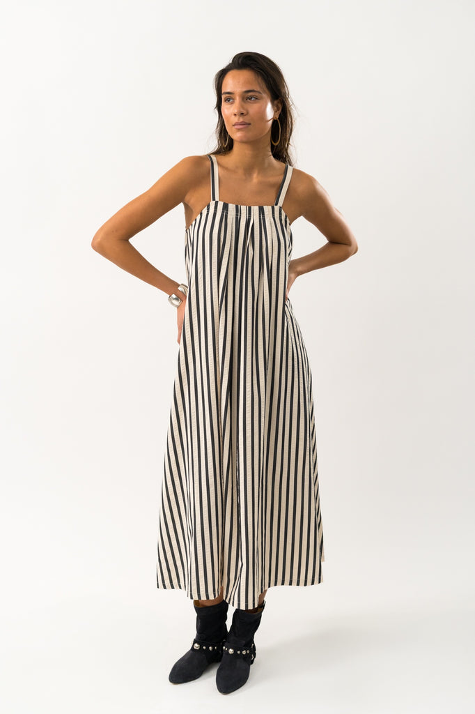 Woman wearing a black and white striped dress on a white background. Lollys Laundry Lungo Striped Sundress.