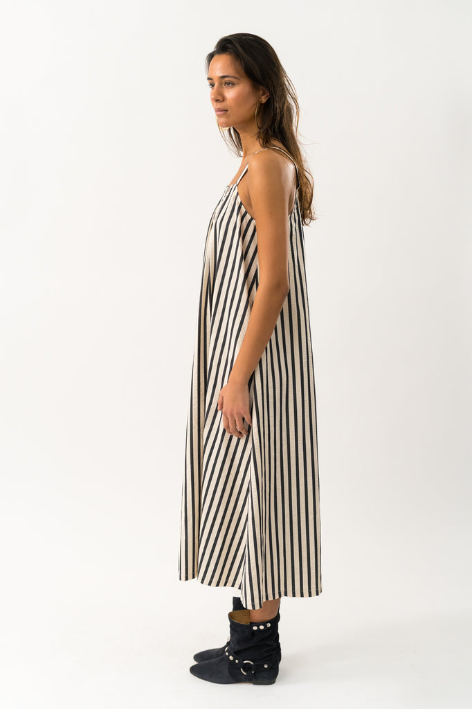 Woman wearing a black and white striped dress on a white background. Lollys Laundry Lungo Striped Sundress.