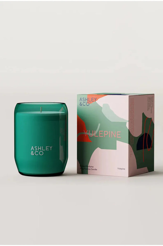 Ashley & Co Ahu Timataka Trace Elements Waxed Perfume Scented Candle Yulepine. Candle in a Teal Glass Vessel sitting beside printed gift box.