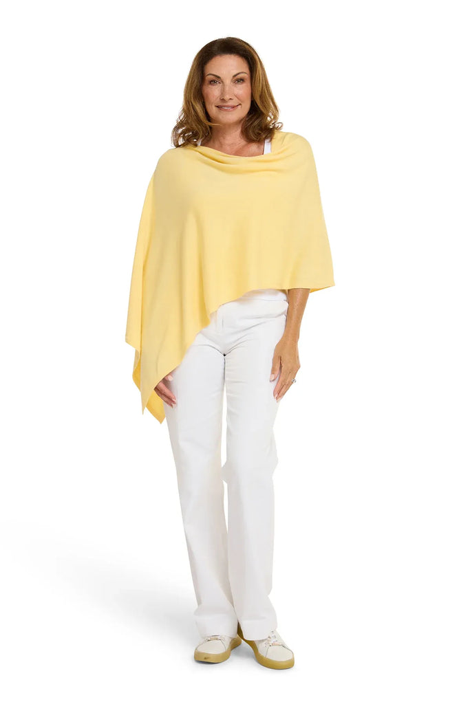 Woman wearing a yellow poncho and white pants on a white background. Alashan Cotton Cashmere Topper in Canary yellow.