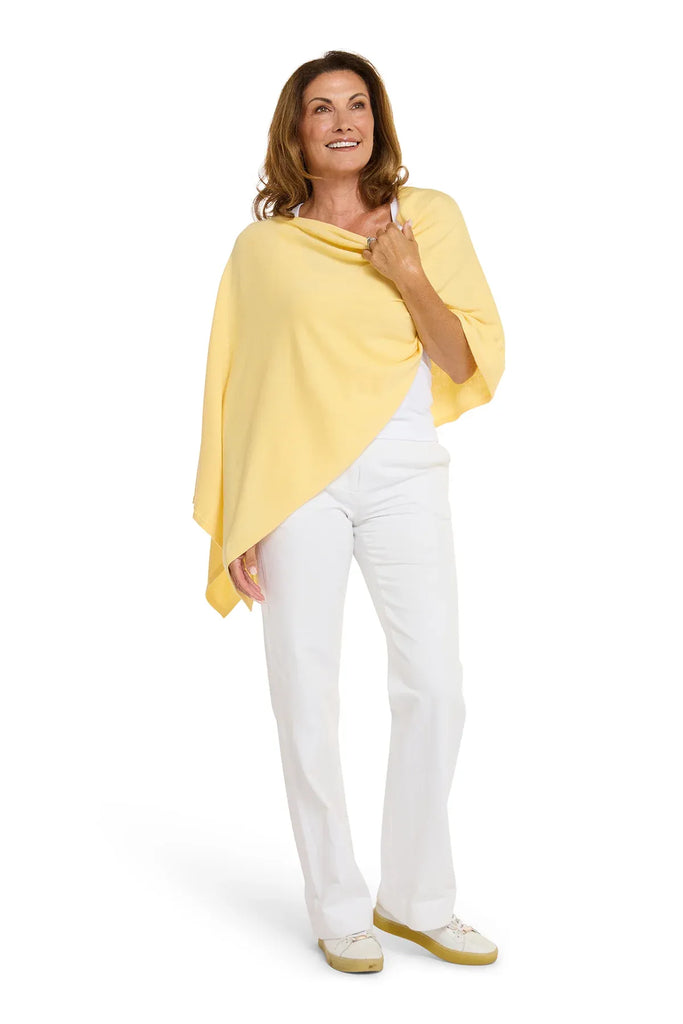 Woman wearing a yellow poncho and white pants on a white background. Alashan Cotton Cashmere Topper in Canary yellow.