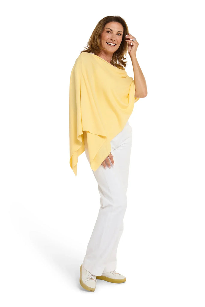 Woman wearing a yellow poncho and white pants on a white background. Alashan Cotton Cashmere Topper in Canary yellow.