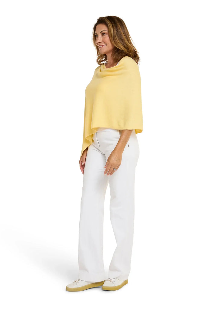 Woman wearing a yellow poncho and white pants on a white background. Alashan Cotton Cashmere Topper in Canary yellow.