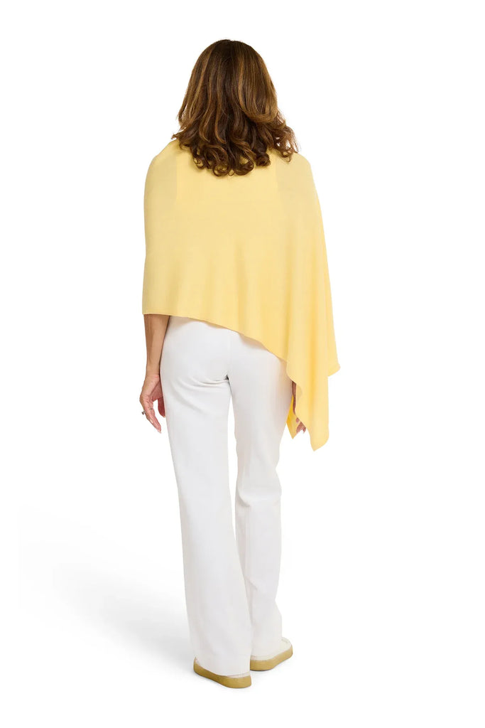 Woman wearing a yellow poncho and white pants on a white background. Alashan Cotton Cashmere Topper in Canary yellow.