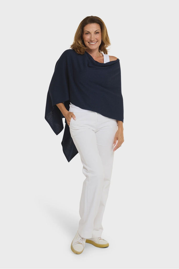 Woman wearing a navy blue poncho over a white top and pants on a white background. Alashan Cotton Cashmere Topper in French Navy.