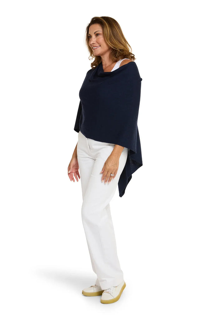 Woman wearing a navy blue poncho over a white top and pants on a white background. Alashan Cotton Cashmere Topper in French Navy.