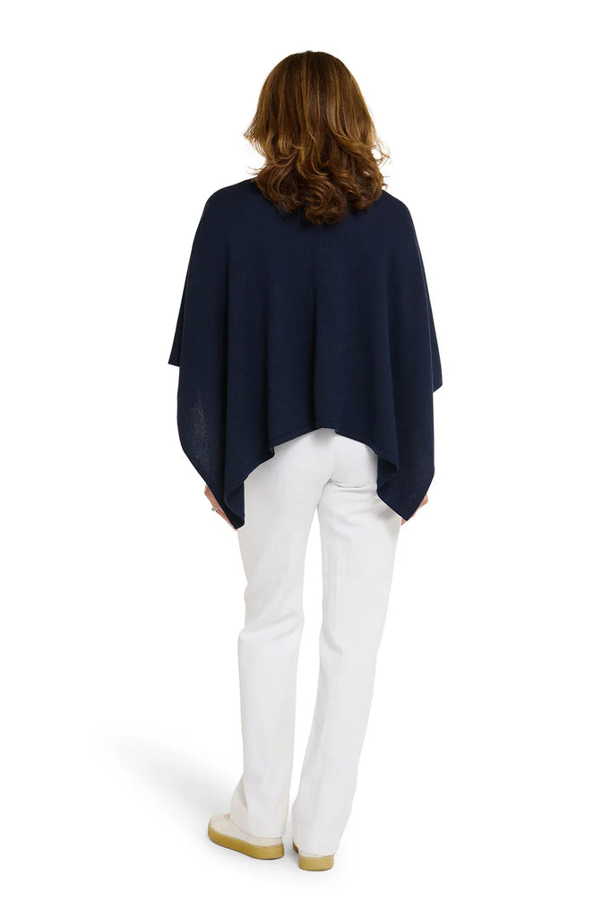 Woman wearing a navy blue poncho over a white top and pants on a white background. Alashan Cotton Cashmere Topper in French Navy.