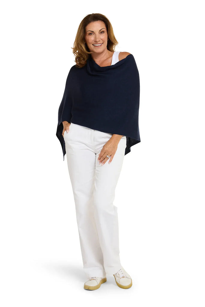 Woman wearing a navy blue poncho over a white top and pants on a white background. Alashan Cotton Cashmere Topper in French Navy.