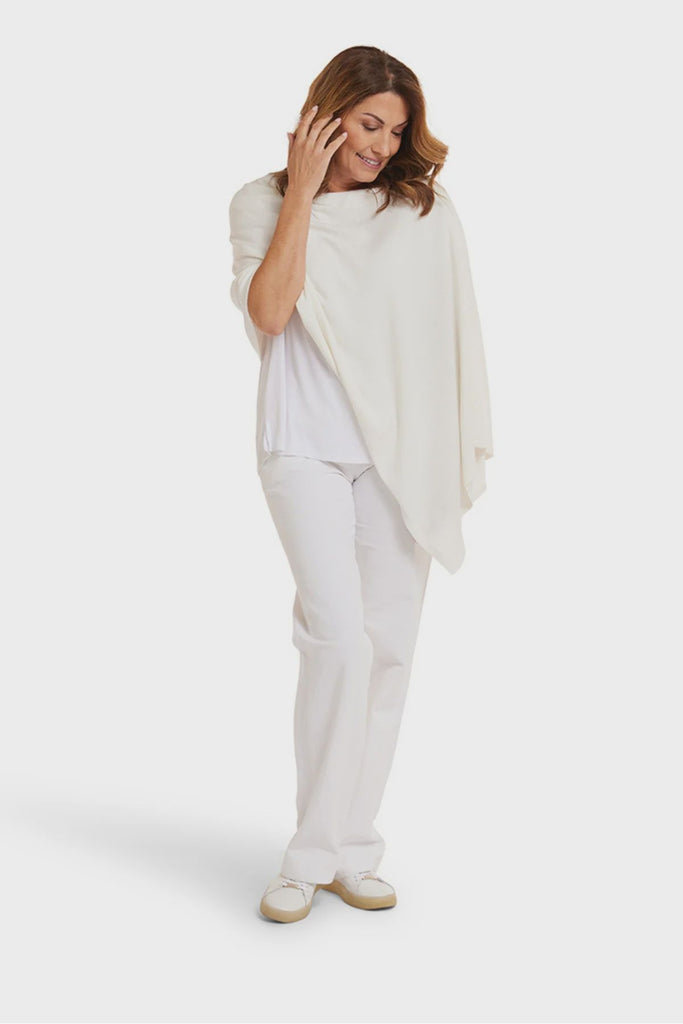 Woman wearing a white shawl over a white top and pants on a white background. Alashan Cotton Cashmere Topper in Off White.