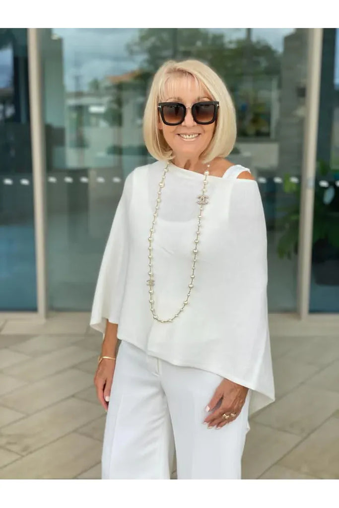 Woman wearing a white shawl over a white top and pants on a white background. Alashan Cotton Cashmere Topper in Off White.