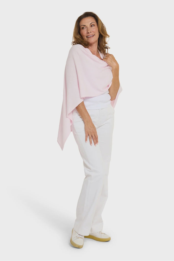 Woman wearing a light pink top and white pants on a white background. Alashan Cotton Cashmere Topper in Pink Sugar.