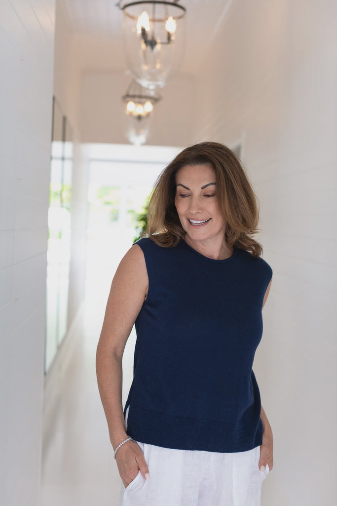 Woman wearing a navy sleeveless top and white pants indoors. Alashan Crest Linen tank in Stargazer navy