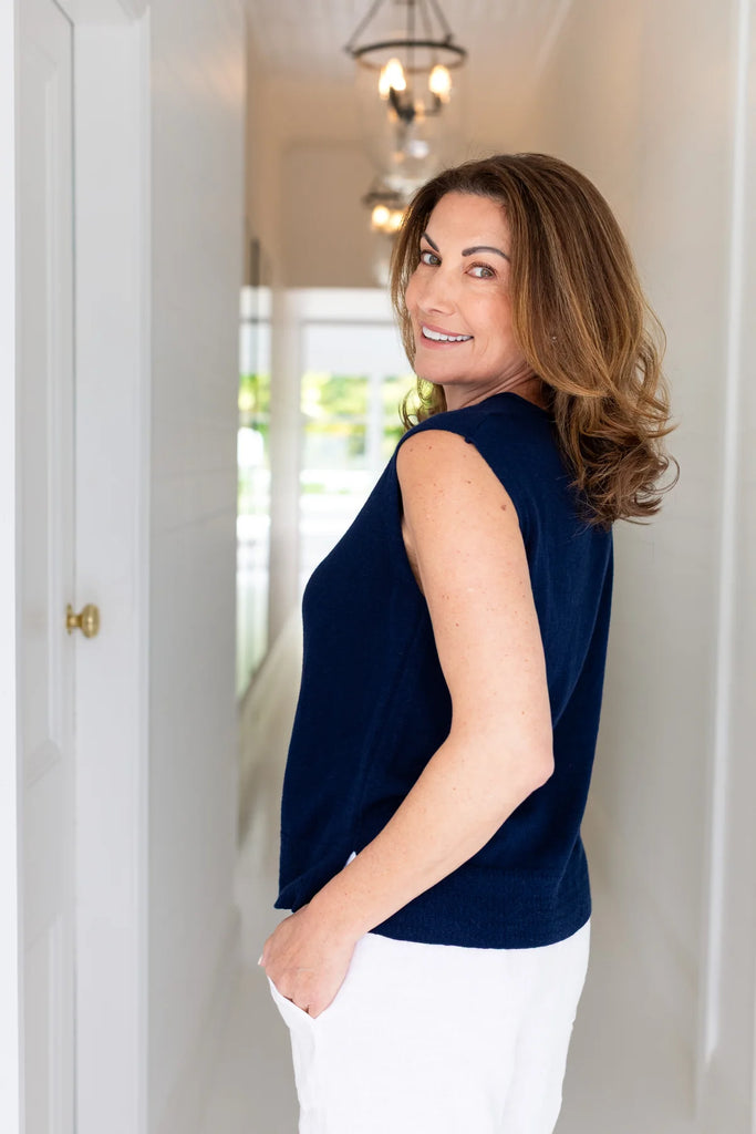 Woman wearing a navy sleeveless top and white pants indoors. Alashan Crest Linen tank in Stargazer navy