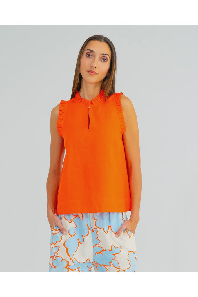 Woman wearing an orange sleeveless top with ruffled details on a plain background. Arlington Milne Lucia Top in Tangerine worn with the Bianca Trouser in Summertime Floral.