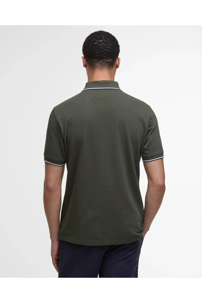Man wearing the Barbour Fielding Tailored Polo Shirt in Olive with navy blue pants against a grey background
