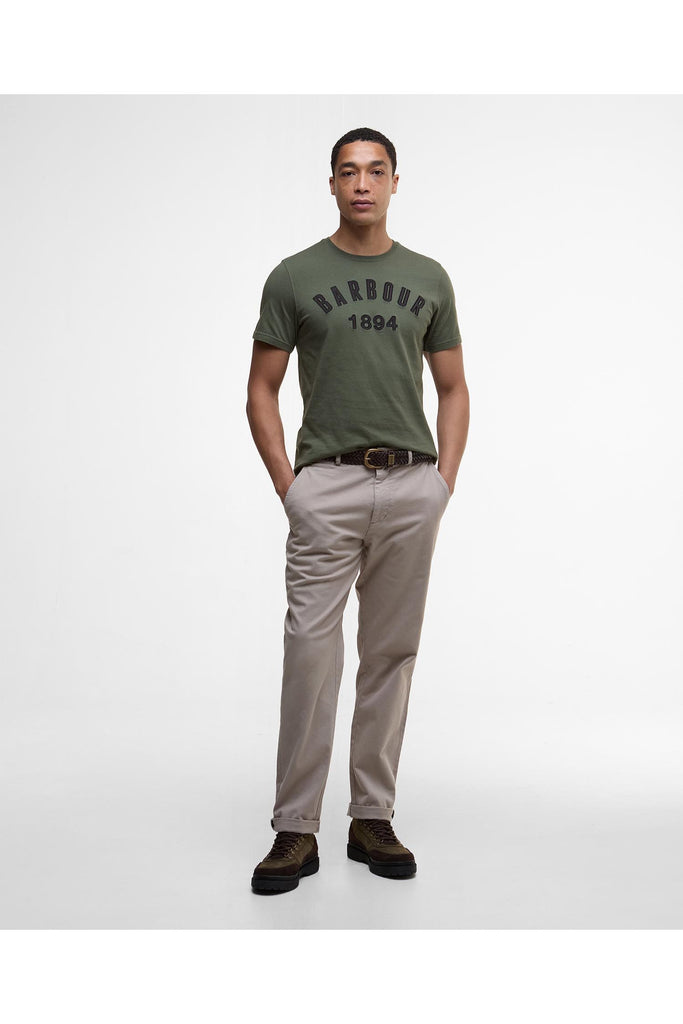 Man wearing a green Barbour t-shirt with 'Barbour 1894' text on a white background. Barbour Hollins Applique T Shirt in Thyme.