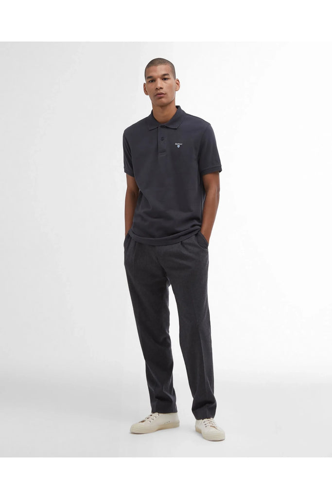 Man wearing a dark polo shirt and pants on a white background. Barbour Original Sports tailored Polo in Navy.