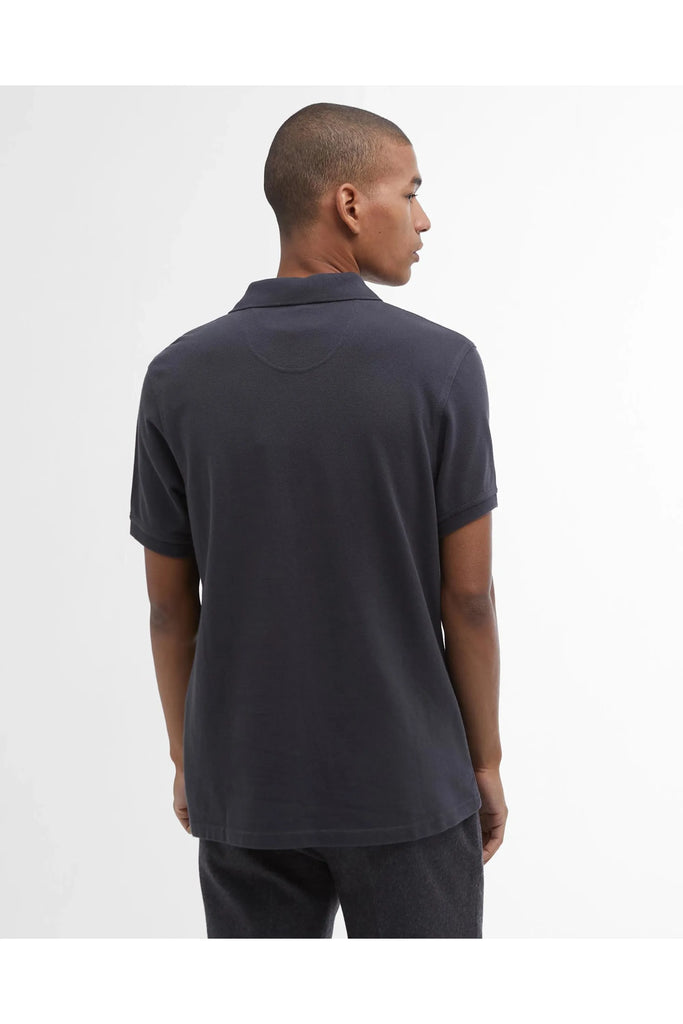 Man wearing a dark polo shirt and pants on a white background. Barbour Original Sports tailored Polo in Navy.