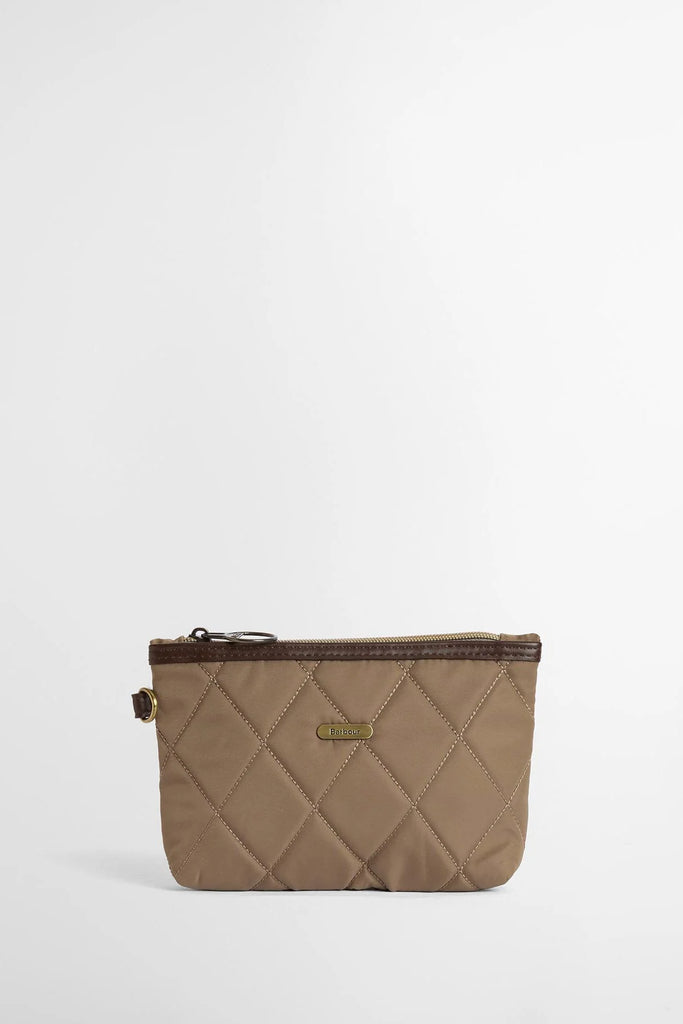 Woman holding a beige quilted handbag against a white background. Barbour Quilted Tote Bag in Sand.