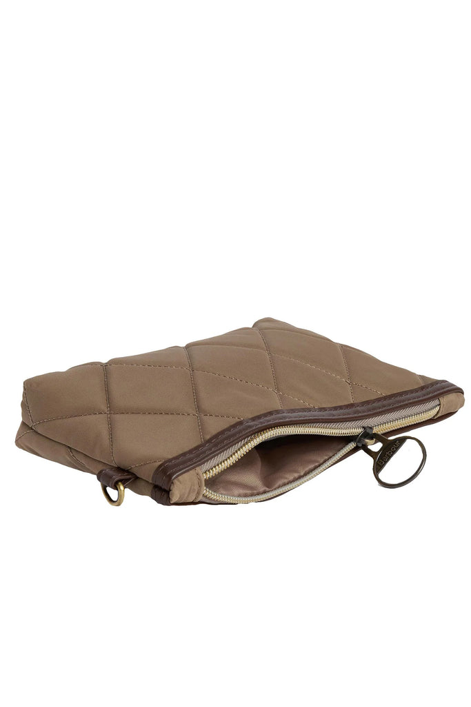 Woman holding a beige quilted handbag against a white background. Barbour Quilted Tote Bag in Sand.