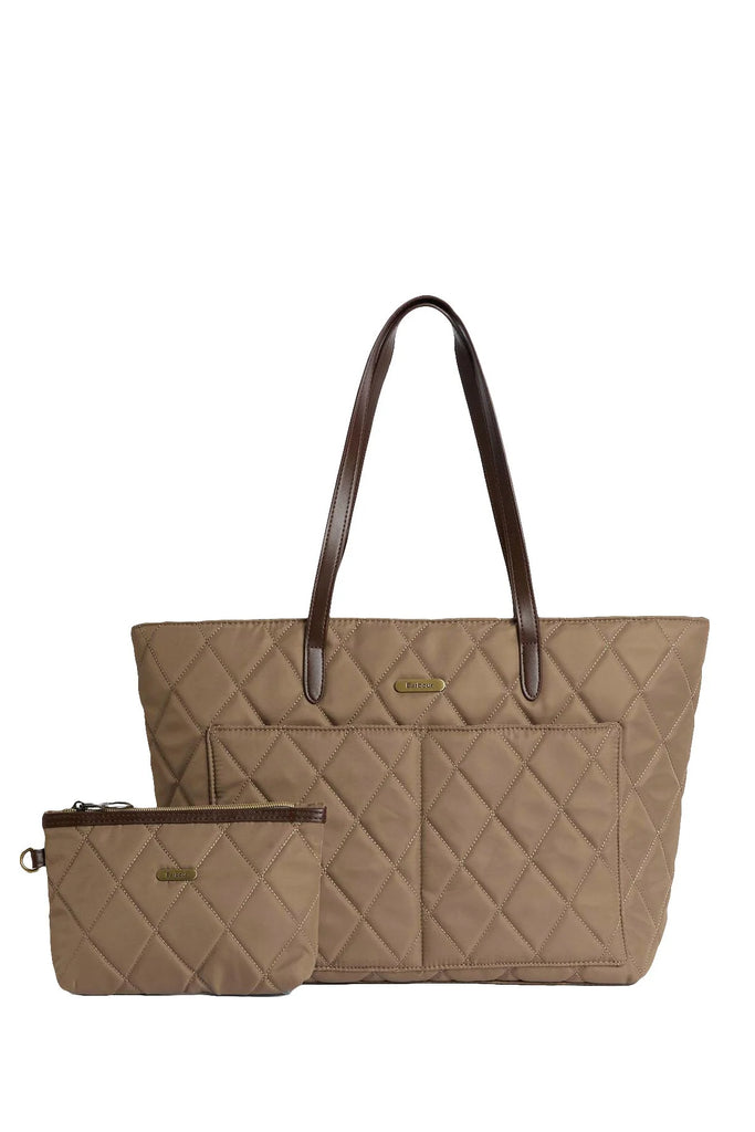Woman holding a beige quilted handbag against a white background. Barbour Quilted Tote Bag in Sand.