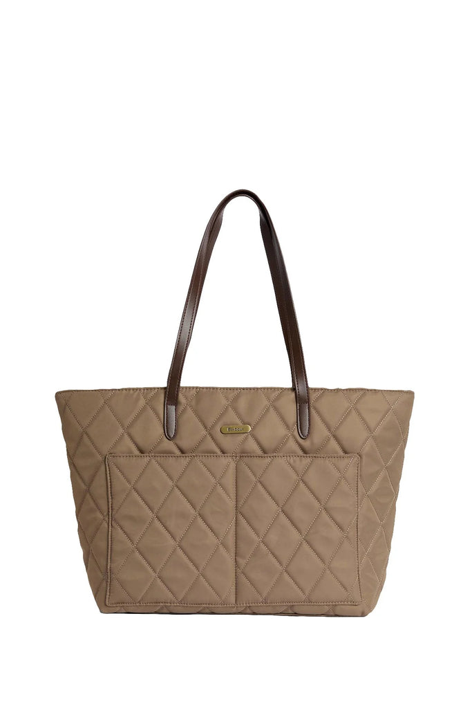 Woman holding a beige quilted handbag against a white background. Barbour Quilted Tote Bag in Sand.