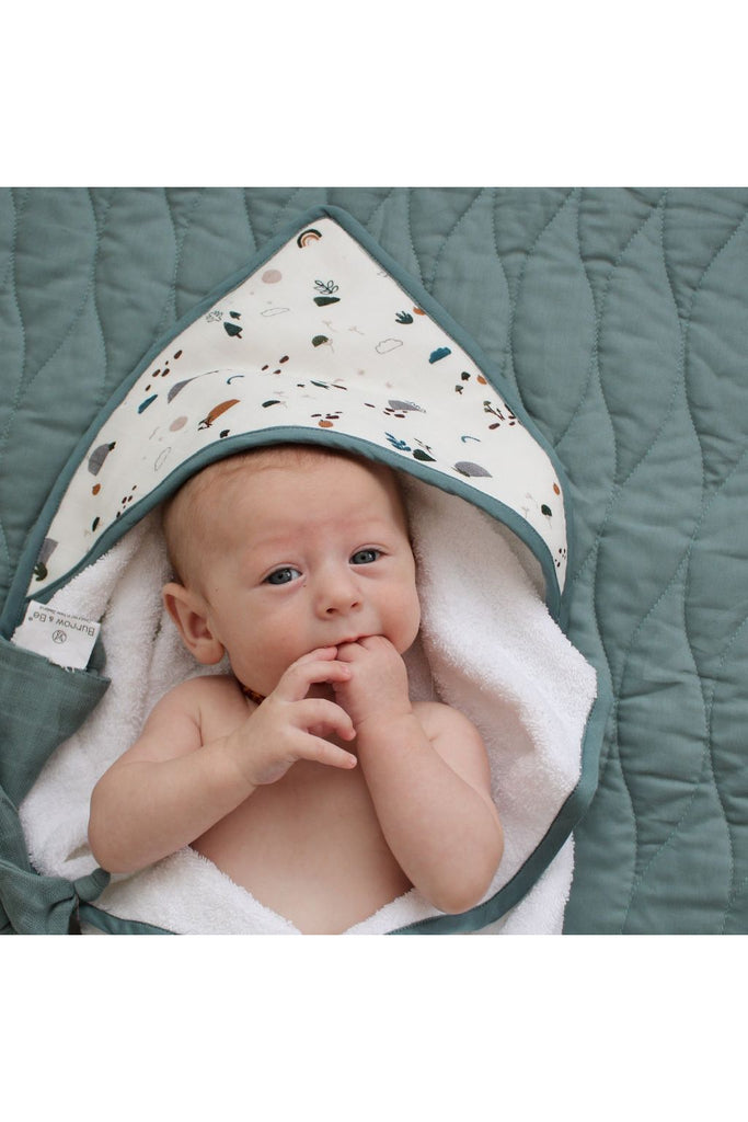 Burrow & Be Garden Treasures Hooded Towel. Image shows Baby wrapped in towel with hood covering the top of the Baby's head.