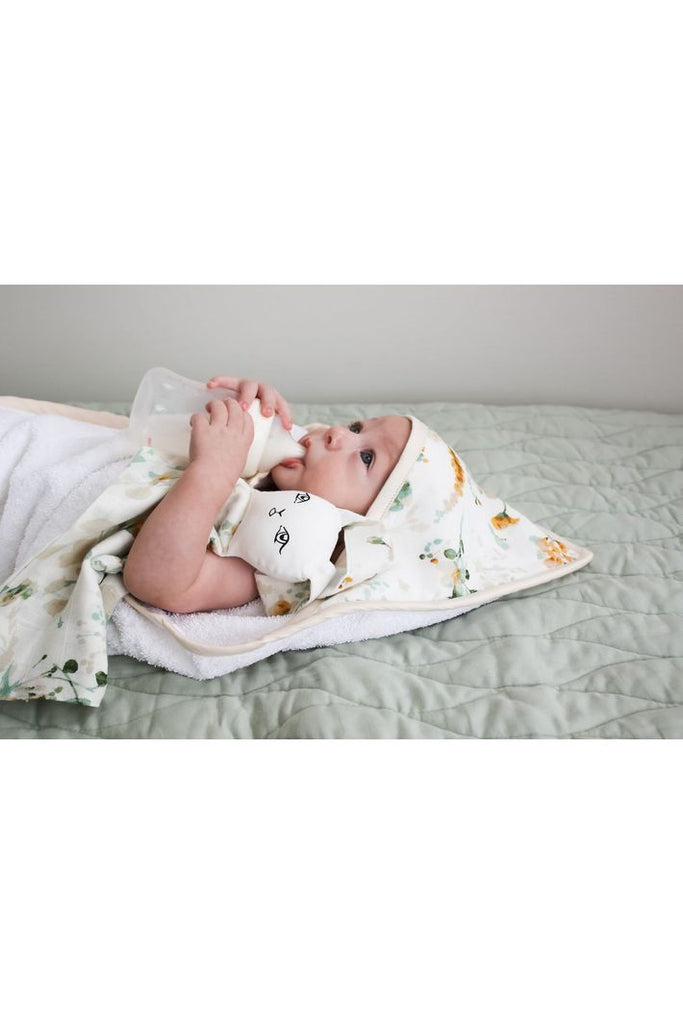 Burrow & Be Spring Melody Hooded Towel . Image shows baby wrapped in hooded towel with hood sitting covering the  top of the baby's head.