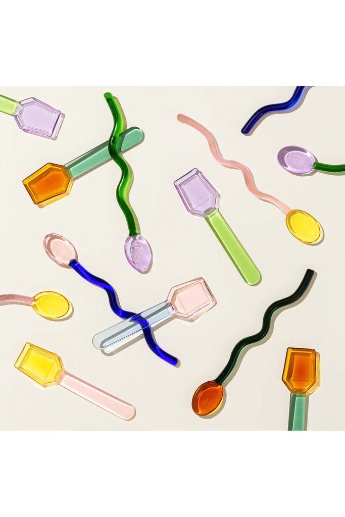 Sucker an array of colourful glass spoons and cocktail stirrers scattered and lying on a light background.