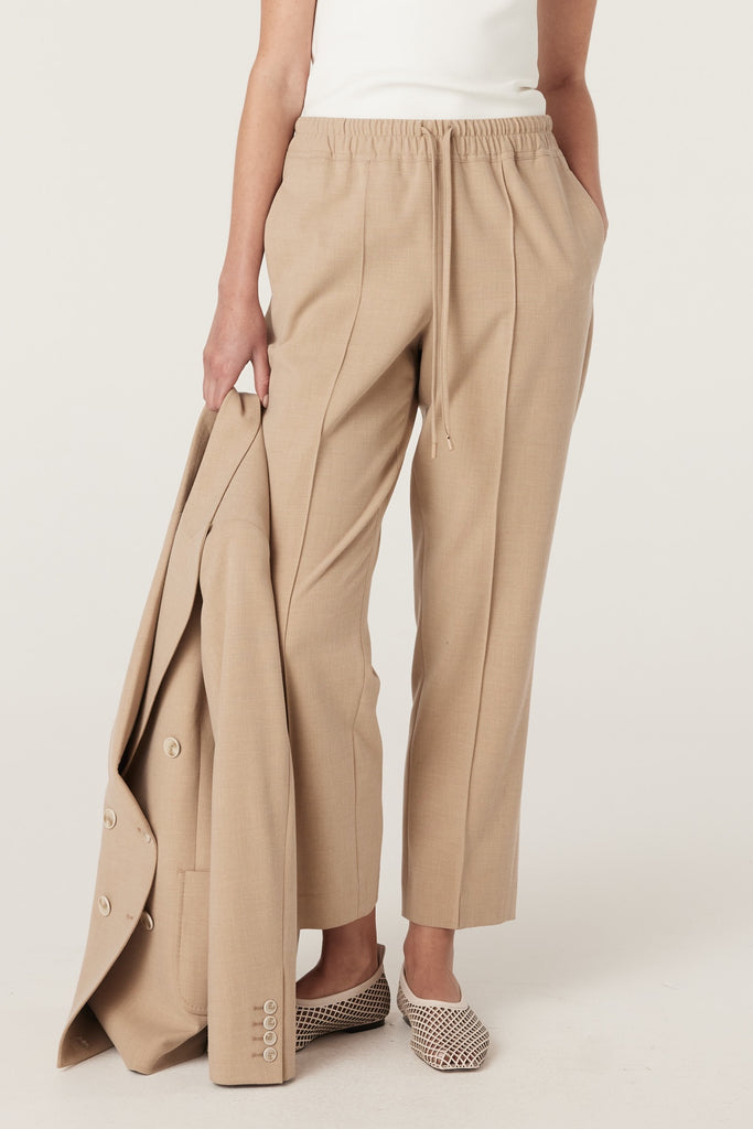 Person wearing beige pants with a white background. Cable Pierre Pant in Light Camel.