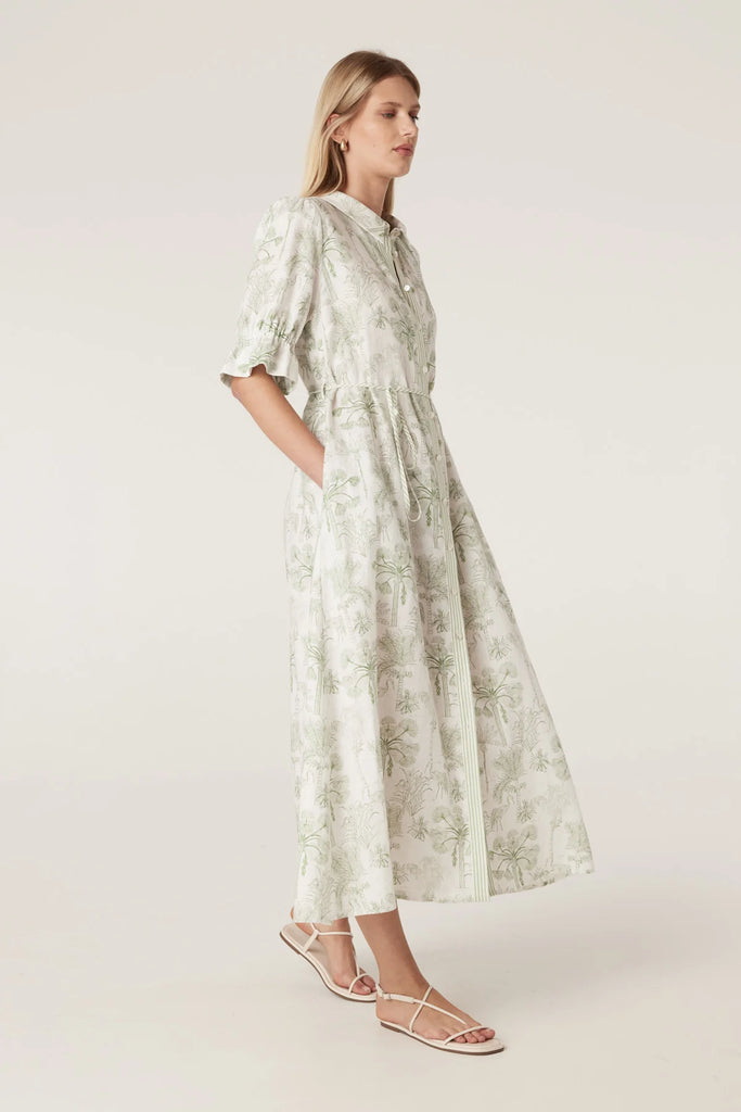 Woman wearing a light-colored dress with a subtle pattern on a plain background. Cable Melbourne Avondale Linen Dress in Palm Print.