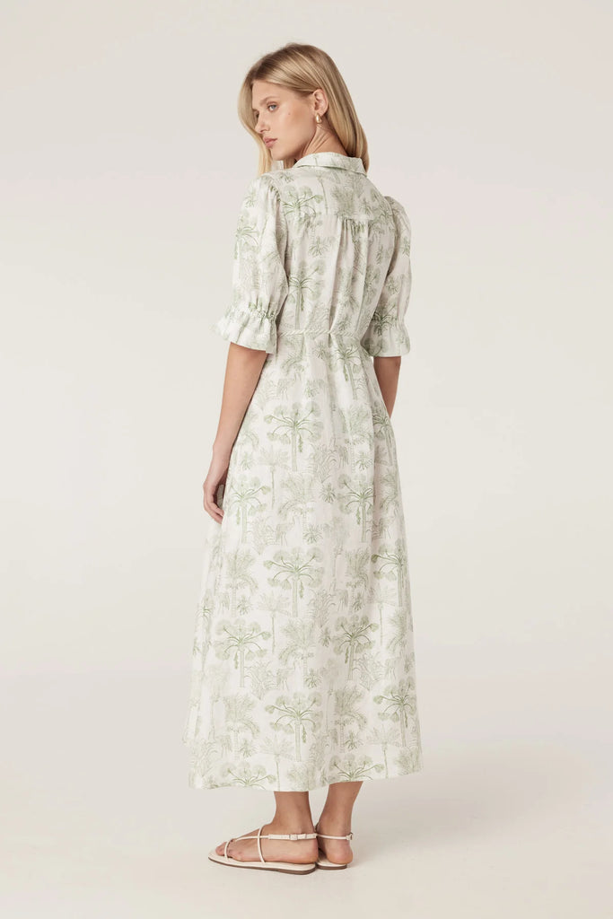 Woman wearing a light-colored dress with a subtle pattern on a plain background. Cable Melbourne Avondale Linen Dress in Palm Print.