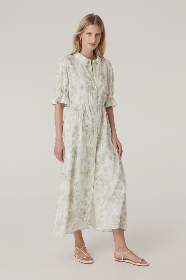Woman wearing a light-colored dress with a subtle pattern on a plain background. Cable Melbourne Avondale Linen Dress in Palm Print.