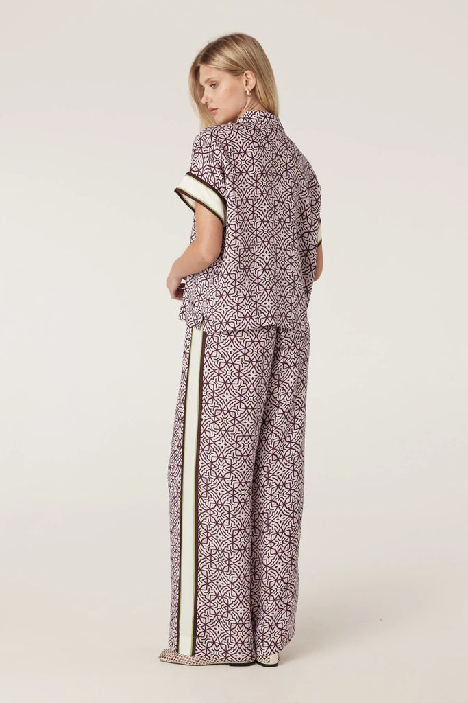 Woman wearing a patterned outfit with a plain background. Cable Melbourne Nova Blouse and matching Pant in Lattice Print.
