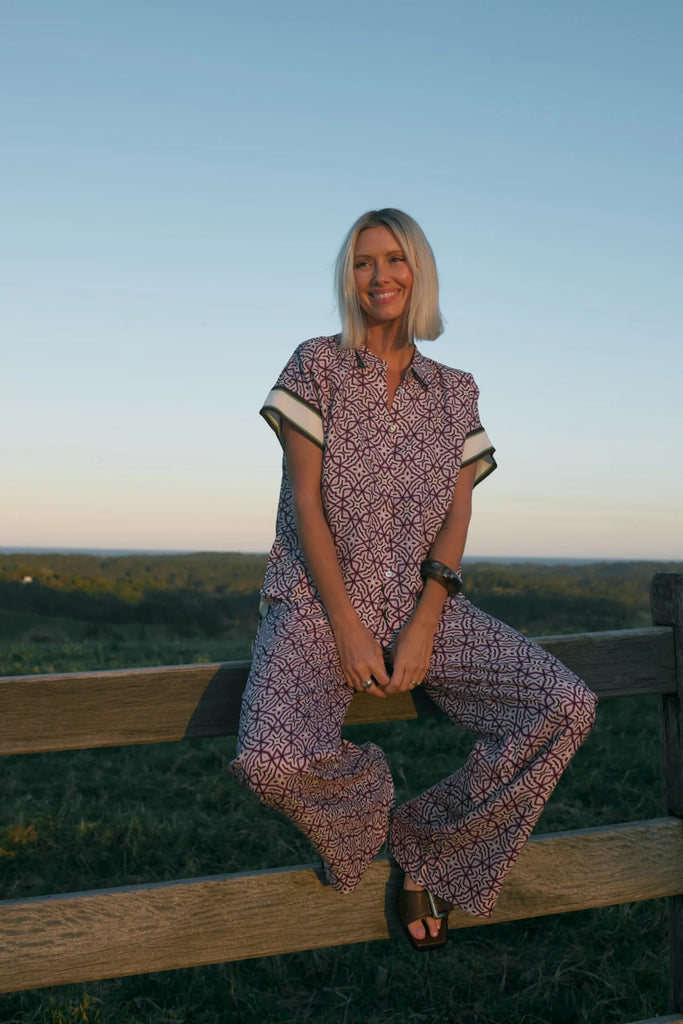 Woman wearing a patterned outfit with a plain background. Cable Melbourne Nova Blouse and matching Pant in Lattice Print.