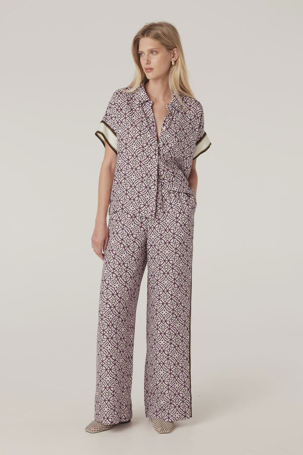 Woman wearing a patterned matching top and pant on a plain background. Cable Melbourne Nova Blouse and Nova Pant in Lattice Print.