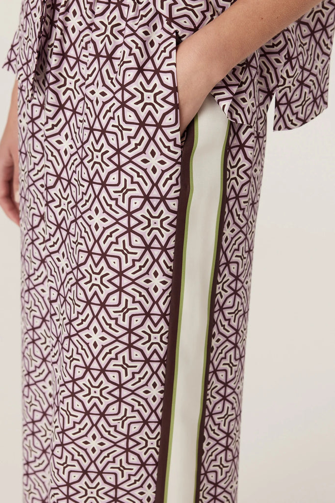 Woman wearing a patterned matching top and pant on a plain background. Cable Melbourne Nova Blouse and Nova Pant in Lattice Print.