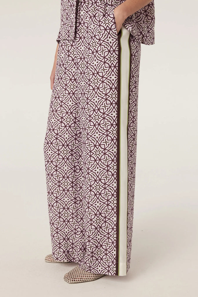 Woman wearing a patterned matching top and pant on a plain background. Cable Melbourne Nova Blouse and Nova Pant in Lattice Print.