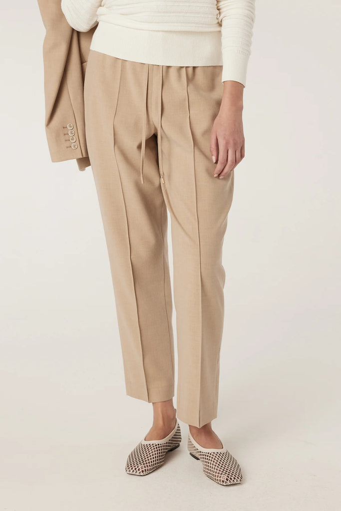 Person wearing beige pants with a white background. Cable Pierre Pant in Light Camel.