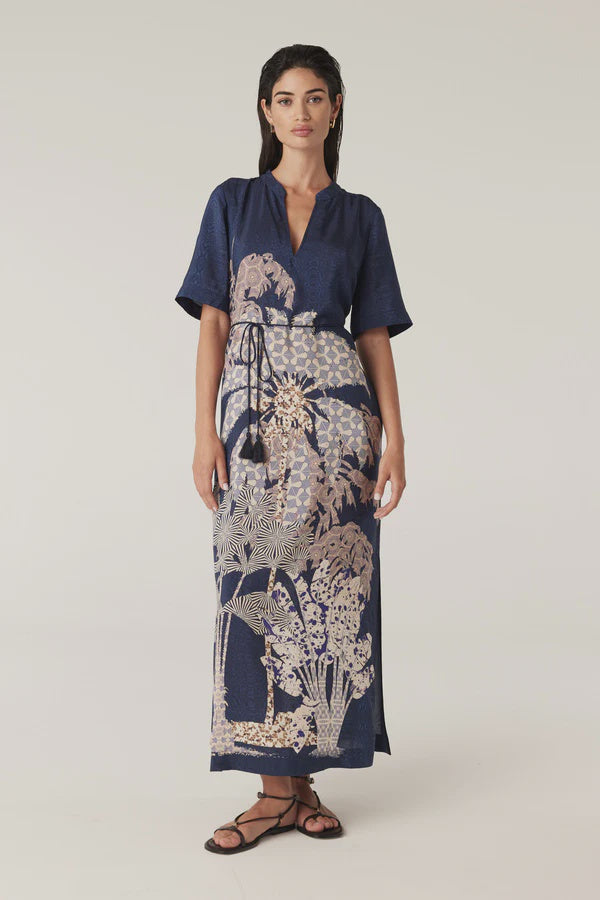 Woman wearing a navy blue top and patterned dress on a white background. Cable Pina Kaftan Dress in Mirage Print.