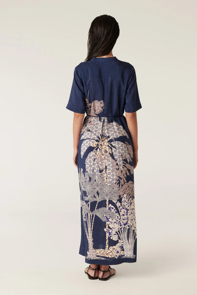 Woman wearing a navy blue top and patterned dress on a white background. Cable Pina Kaftan Dress in Mirage Print.