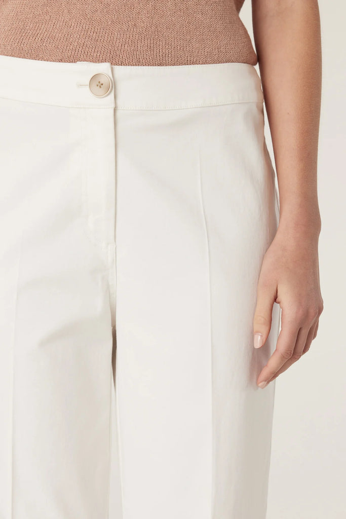 Woman wearing a beige sleeveless top and white pants on a plain background, Cable Porto Pant in white.