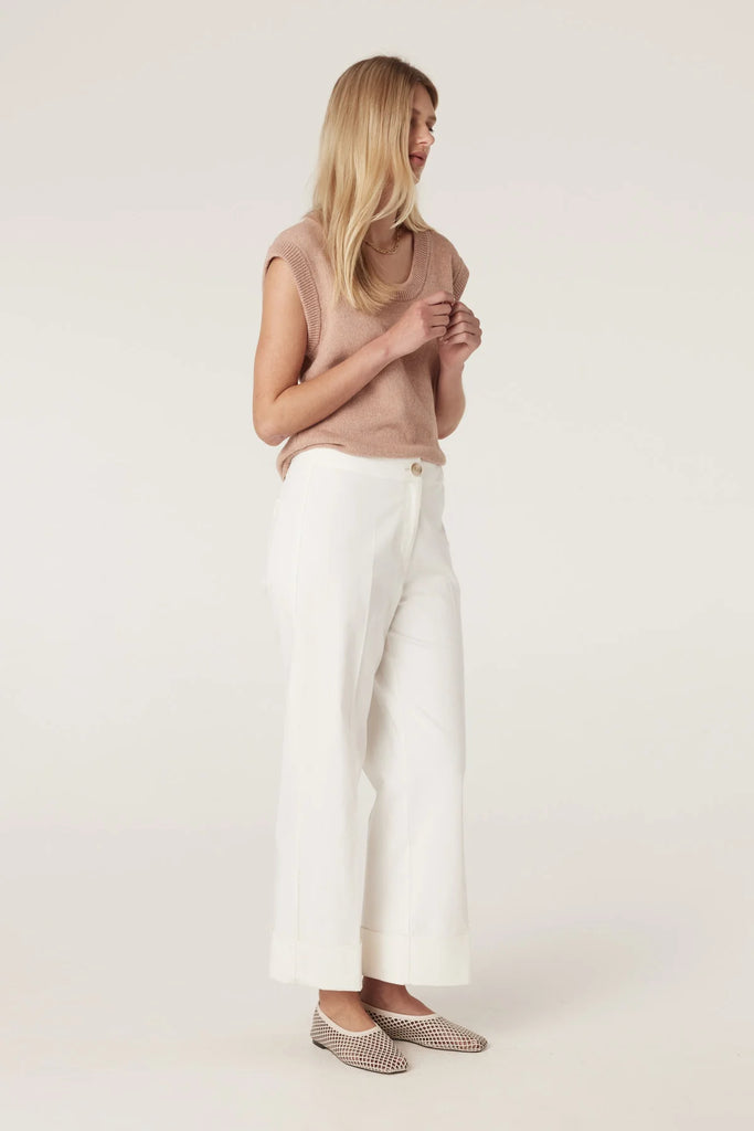 Woman wearing a beige sleeveless top and white pants on a plain background, Cable Porto Pant in white.