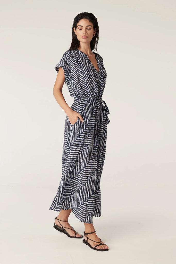 Woman wearing a blue and white patterned dress on a plain background. Cable Seabreeze dress in chevron print.