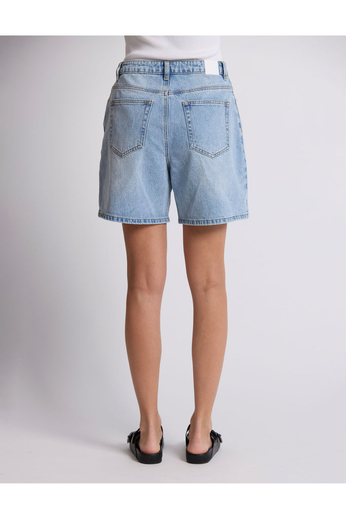 Person wearing denim shorts on a plain background. Stella and Gemma Light Blue Denim Emily Shorts.