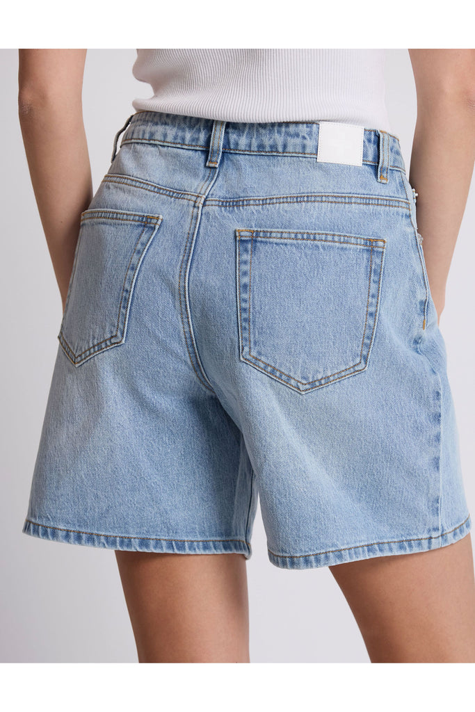 Person wearing denim shorts on a plain background. Stella and Gemma Light Blue Denim Emily Shorts.